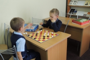 Два друга-первоклассника играют в шашки.