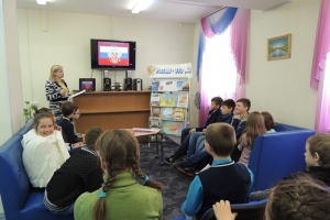 Ведущая мероприятия объясняет юным читателям значение цветов флага России.